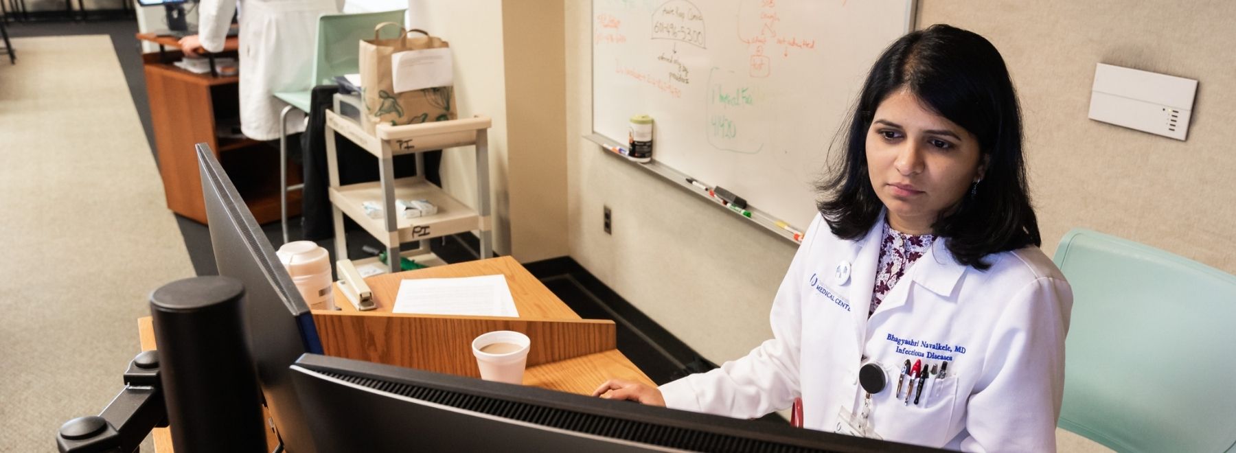 An infectious disease specialist reviews information on a computer.